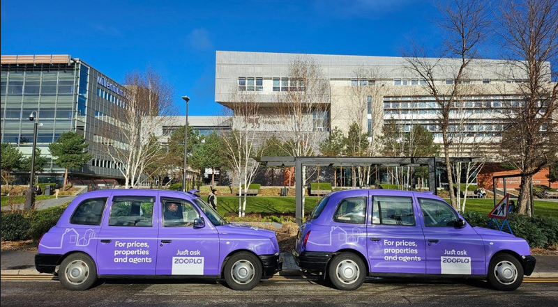 Two London taxis emblazoned with Zoopla's purple livery