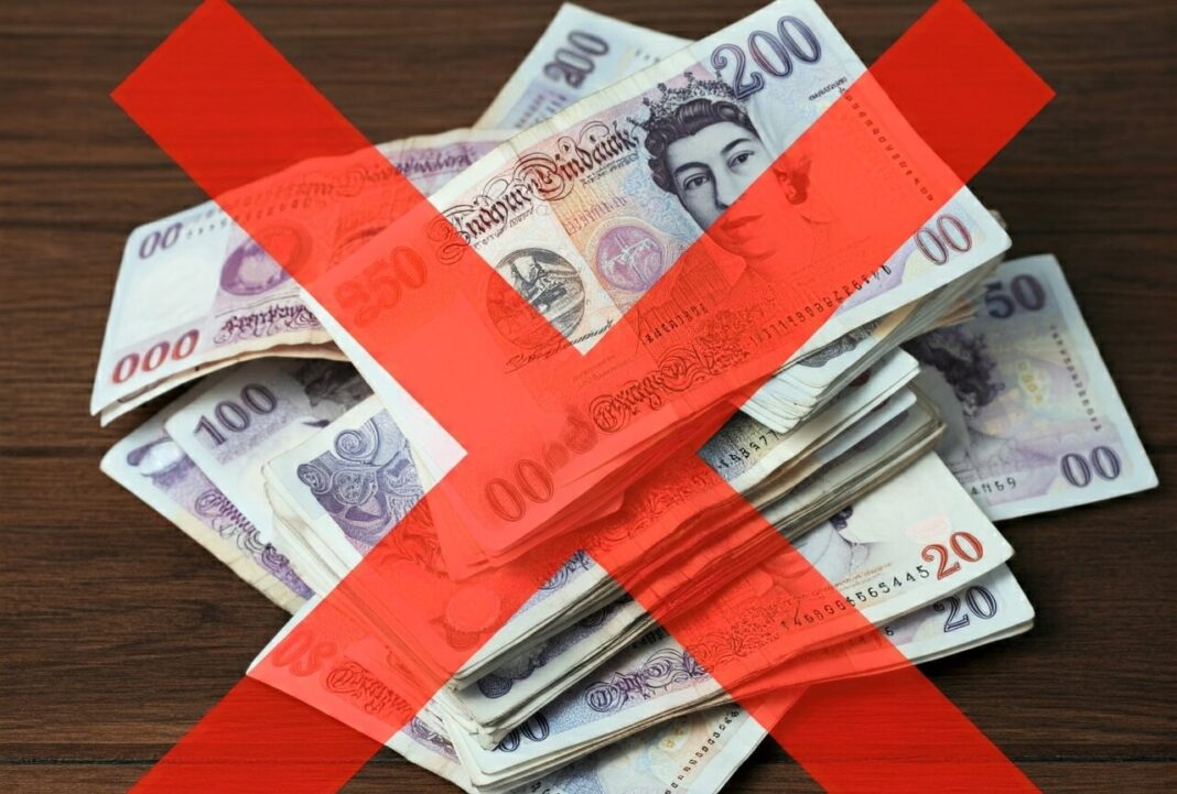 A picture of UK money with a cross over it